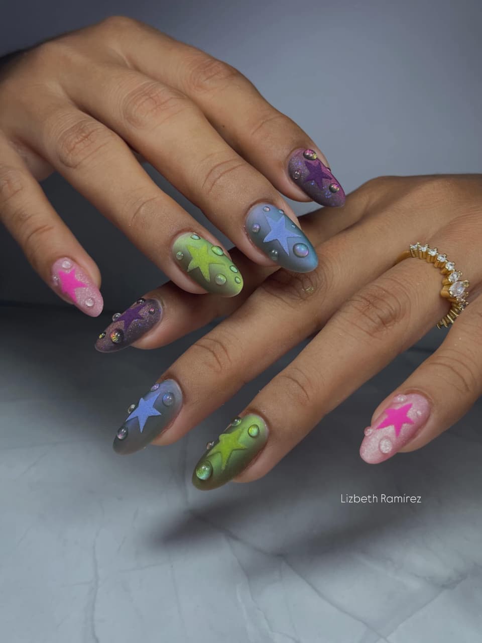 Detalle lateral de uñas rosa con flores doradas