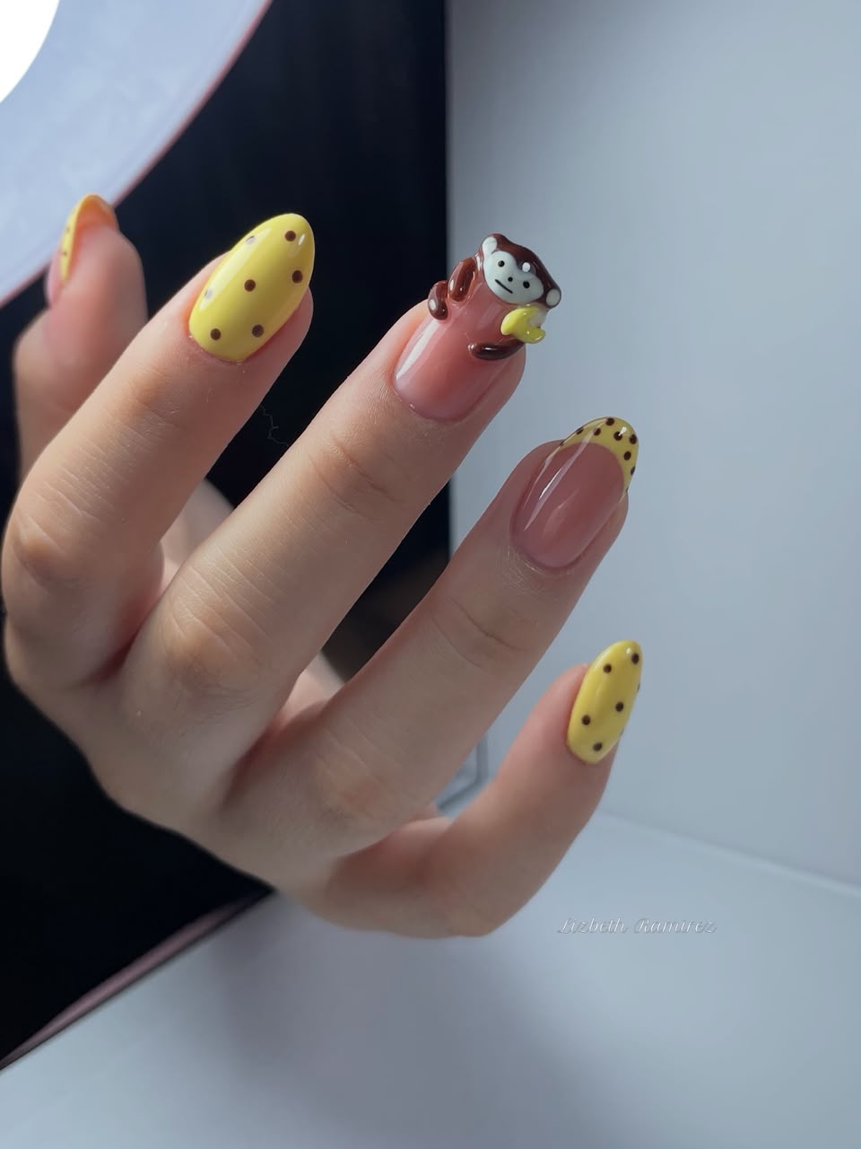 Detalle de uñas amarillas con lunares y monito en 3D